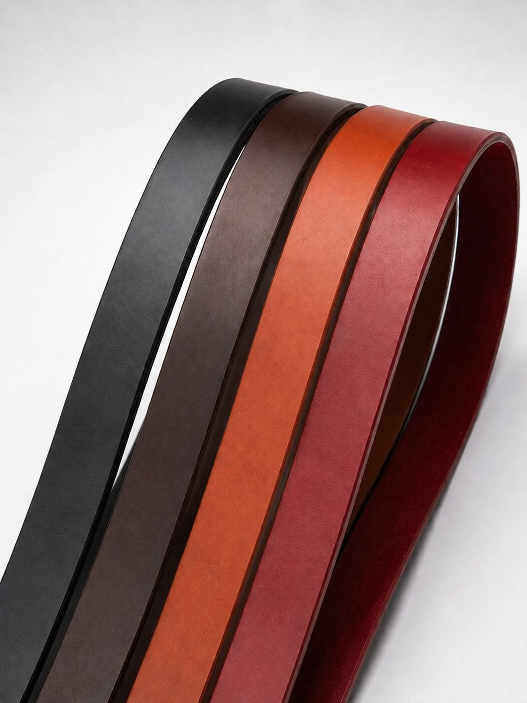Leather belt blanks in black, dark brown, tan and red laid side by side